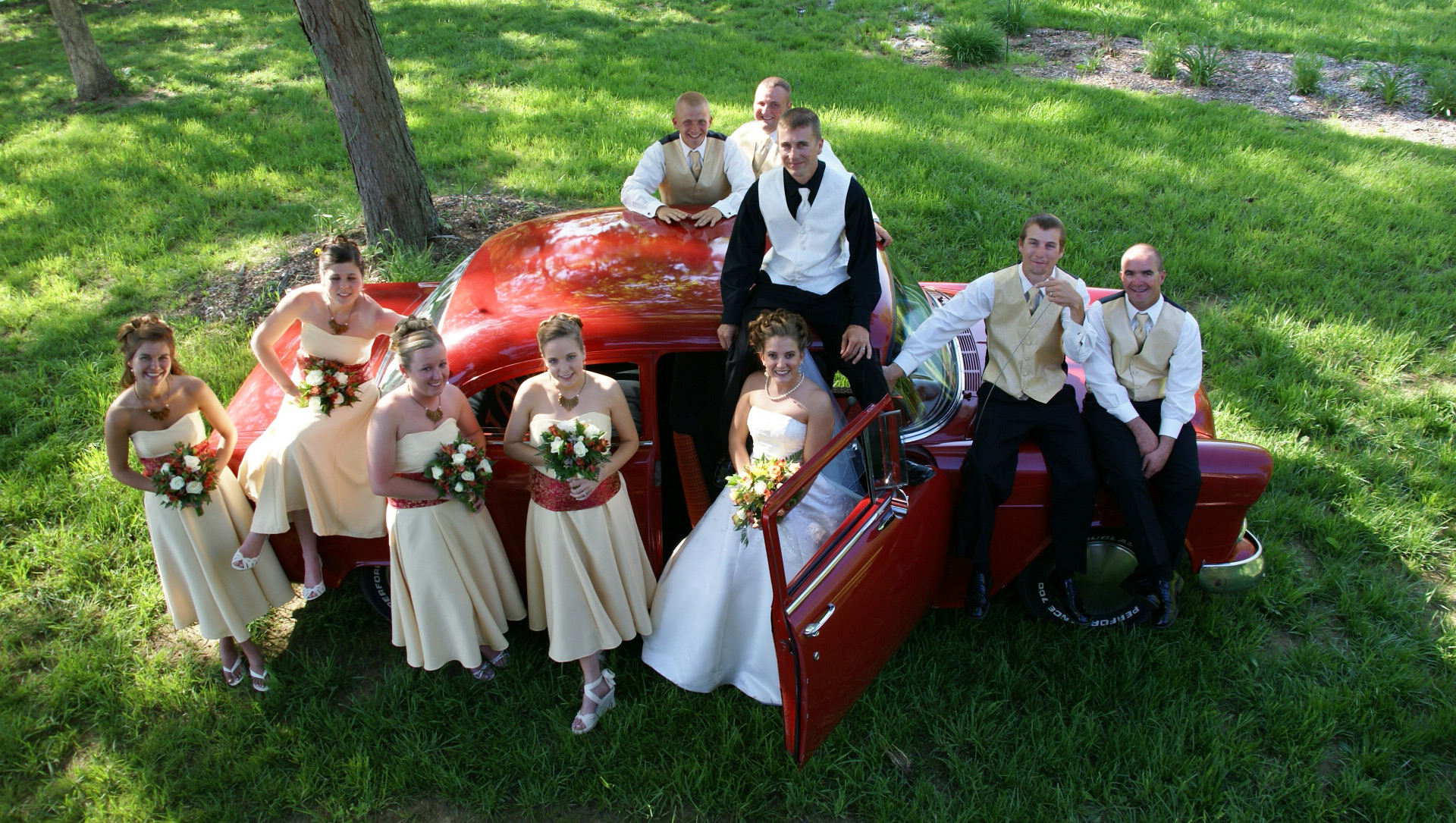 bridal party with red classic car
