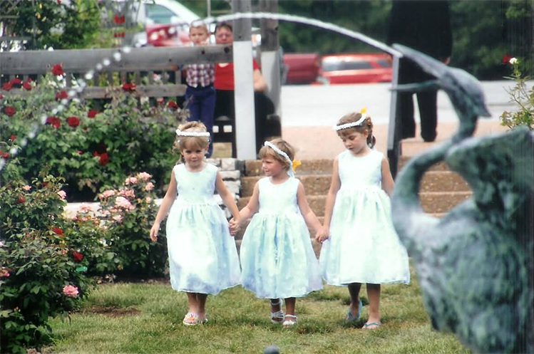 flower girl trio framed by water from fountain